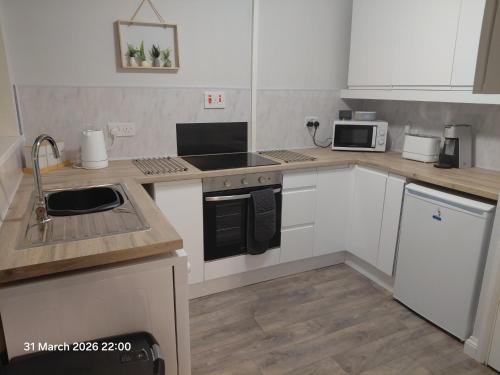 a kitchen with white cabinets and a stove top oven at Flat by the sea in Paignton