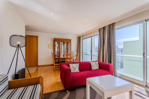 a living room with a red couch and a table at GuestReady - Santo Amaro apartment in Vila Franca do Campo