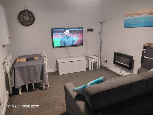 a living room with a couch and a tv on the wall at Flat by the sea in Paignton