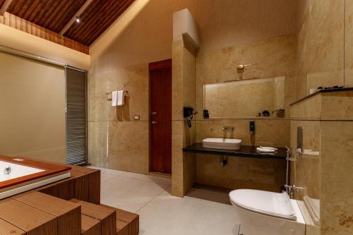 a bathroom with a toilet and a sink and a tub at Vynza Resort Vythiri in Vythiri