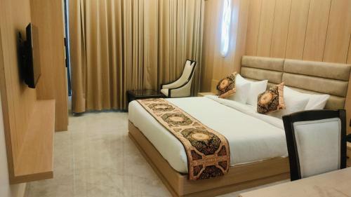 a bedroom with a bed and a chair in it at Hotel Avnish Near To Tajmahal in Agra