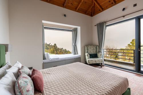 a bedroom with a bed and a couch and windows at Summerfield Manor 5 Bedroom Garden Estate in Bhīm Tāl