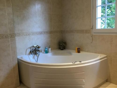 a white tub in a bathroom with a window at belle maison 3000 m de Paris in Cachan