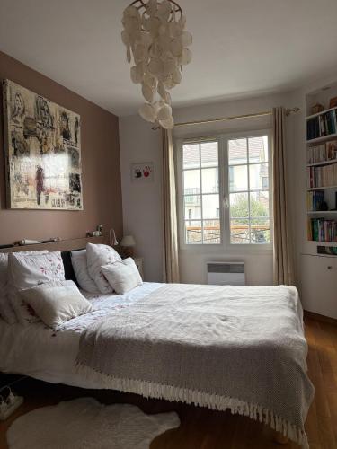 a bedroom with a bed with white sheets and a window at belle maison 3000 m de Paris in Cachan