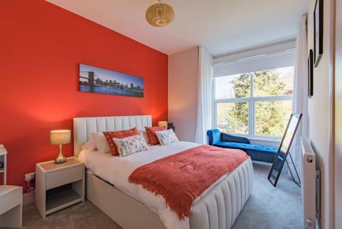 a bedroom with orange walls and a bed and a window at Folkestone Apartments in Folkestone