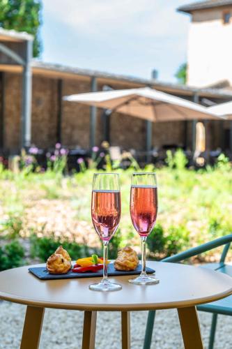 two glasses of wine are sitting on a table at Demeures et Châteaux l'Abbaye Caladoise in Villefranche-sur-Saône