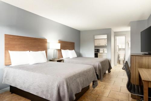 a hotel room with two beds and a flat screen tv at Home Inn & Suites in Orlando