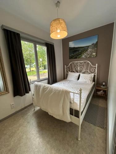 a bedroom with a white bed and a window at Au Bout du Monde - Dinant in Waulsort