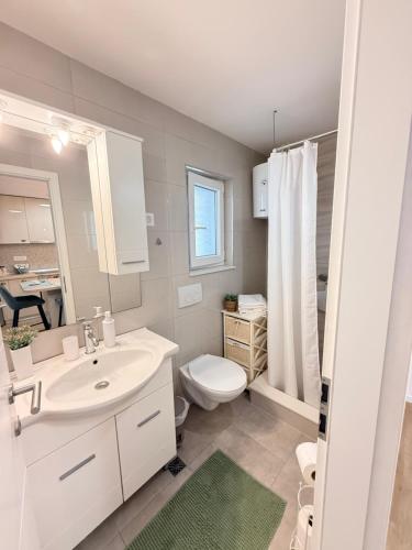 a bathroom with a white sink and a toilet at Apartments Garmaz in Podgora