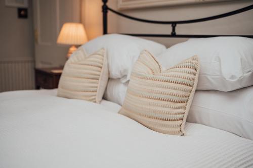 a bed with white pillows with a heart pillow at The Farthings Somerset in Taunton