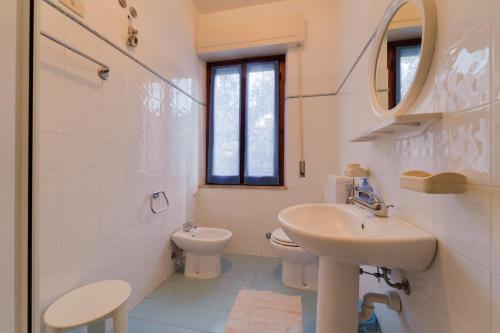 a white bathroom with a sink and a toilet at Appartamento Pomonte la Posta - Goelba in Pomonte