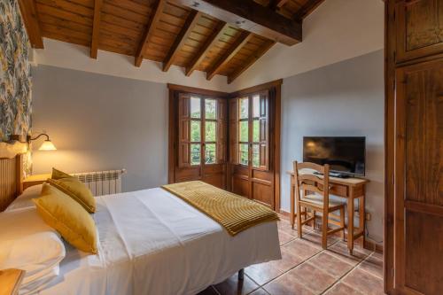a bedroom with a bed and a desk and a television at Hotel La Lluriga in La Galguera