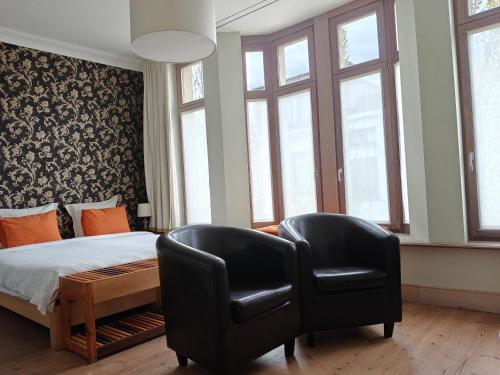 sypialnia z dwoma krzesłami, łóżkiem i oknami w obiekcie Bed & Breakfast Exterlaer w Antwerpii