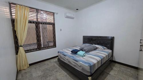a bedroom with a bed in a room with a window at Rumah Mewah Johar in Pontianak