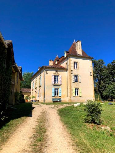 a large building on a field with a dirt road at Domaine Le Berdoy in Montesquiou
