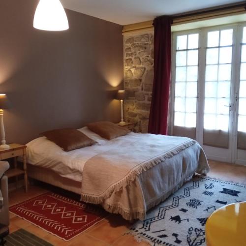 a bedroom with a bed and a large window at LE MASSITROU - chambre d'hôte - Table d'hôte in Nedde