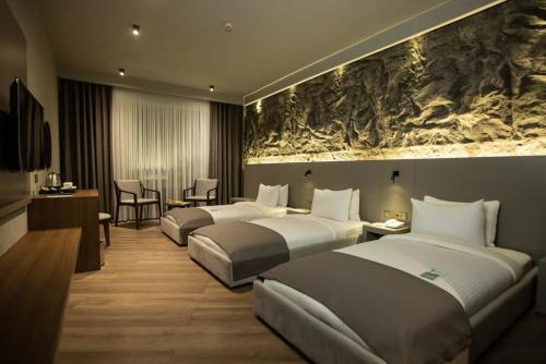 a hotel room with three beds and a painting on the wall at The Erzurum Hotel in Erzurum