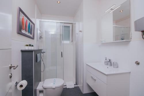 a white bathroom with a shower and a toilet at Relax Apartments in Novalja