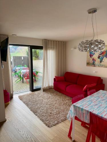 a living room with a red couch and a table at Casa con vista Sciliar centro paese PINK con parcheggio privato in Völs am Schlern