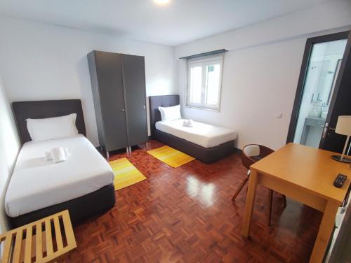 a small room with two beds and a desk at Lisbon Airport GuestHouse GAL Olivais Conforto, Terraço e Localização Premium nos Olivais in Lisbon
