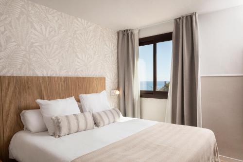 a bedroom with a white bed with a window at Feelathome Vil-la Romana in Tossa de Mar