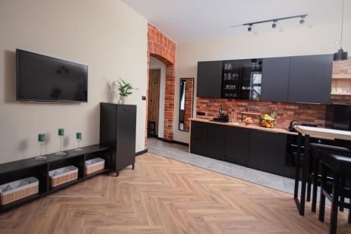 a kitchen with black cabinets and a flat screen tv at Apartament Podchorążych Dęblin in Dęblin
