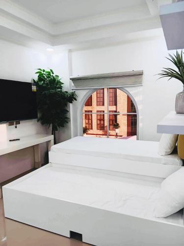a white room with two beds and a tv at Promesa White House in San Fernando