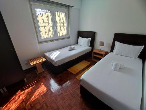 a small room with two beds and a window at Lisbon Airport GuestHouse GAL Olivais Conforto, Terraço e Localização Premium nos Olivais in Lisbon