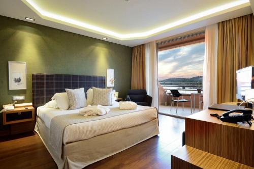 a bedroom with a large bed and a view of the water at Royal Paradise Beach Resort & Spa in Potos