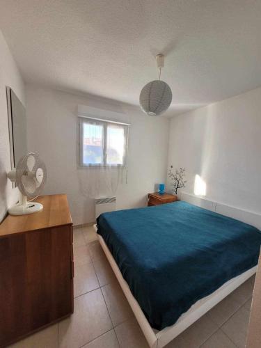 a bedroom with a large bed with a blue blanket at Maison à proximité de la plage in Prunete