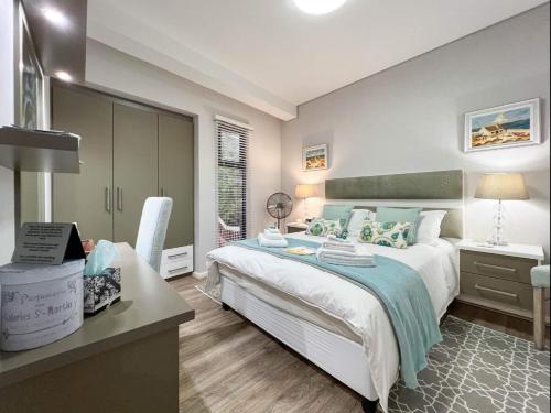 a bedroom with a large bed with a desk and a window at Yadah Guest House in Mossel Bay