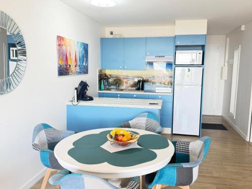 a kitchen with a table with a bowl of fruit on it at Appartements front de mer 2 piscine chauffées la pironnière Residence de l'estrand in Les Sables-d'Olonne
