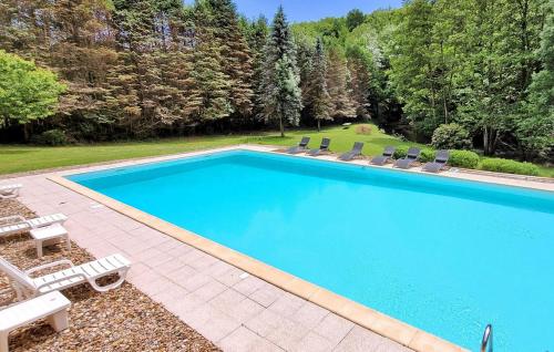 a large swimming pool with chairs and a swimming poolvisor at La Vieille Forge in Sarrazac