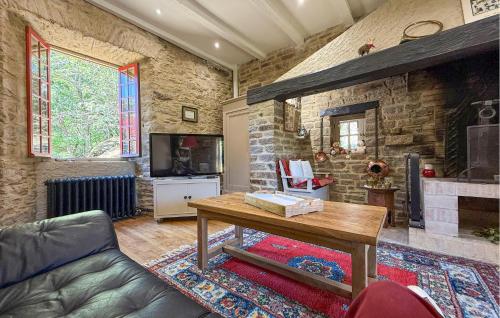 a living room with a table and a stone fireplace at La Vieille Forge in Sarrazac