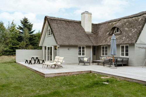 a house with a large wooden deck in front of it at Thatched Hideaway At Svinkløv Forest Edge in Fjerritslev