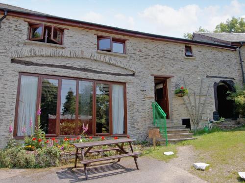 a brick house with a bench in front of it at Whortleberry Cottage in Wheddon Cross