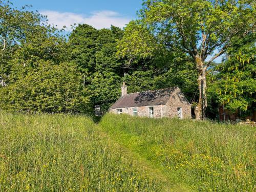 an old stone house on a hill in a field at Craigrannoch Cottage in Rockcliffe