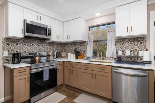 a kitchen with white cabinets and stainless steel appliances at Spacious 4BR Home with Pool BBQ & Games in Grand Prairie