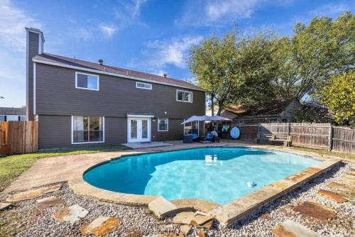 a swimming pool in front of a house at Spacious 4BR Home with Pool BBQ & Games in Grand Prairie