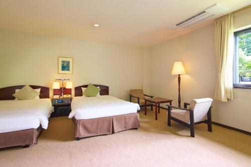 a hotel room with two beds and a desk and a chair at Hotel Marroad Karuizawa in Karuizawa