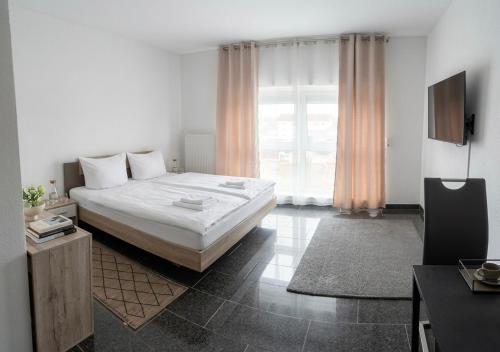 a bedroom with a large white bed and a television at Pent - Aparthotel Crailsheim in Crailsheim