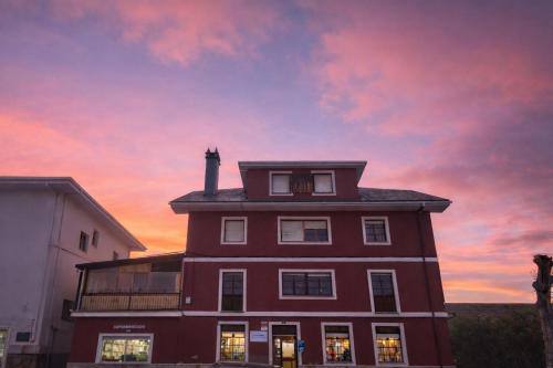 a red building with a sunset in the background at Casa Rural Nito - Naturaleza y Descanso en Asturias in Villayón
