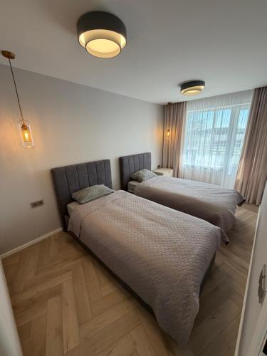 a bedroom with two beds and a large window at JAVA ESTATE apartment in Rēzekne