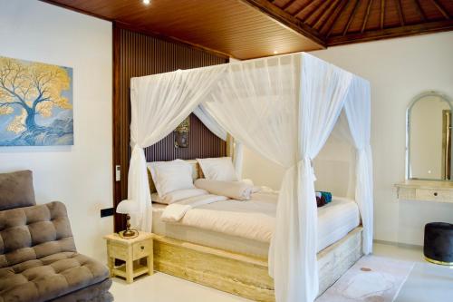 a bedroom with a canopy bed and a chair at Inaya Private Pool Villa in Ambat