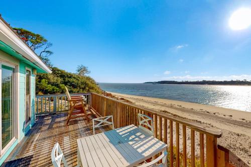a deck with a table and chairs on the beach at Halsell's Hideaway in Indian Pass