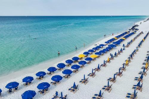 a beach with blue and yellow umbrellas and the ocean at Pelican Beach Resort 1502 in Destin