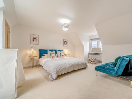 a white bedroom with a bed and a blue chair at Springbank in Brodick
