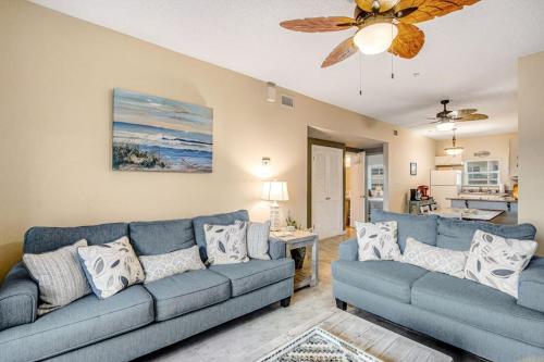 a living room with two blue couches and a ceiling fan at Villas on the Gulf J6 in Pensacola Beach