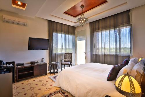 a bedroom with a large bed and a flat screen tv at Palais Amador in Oulad Mazoug