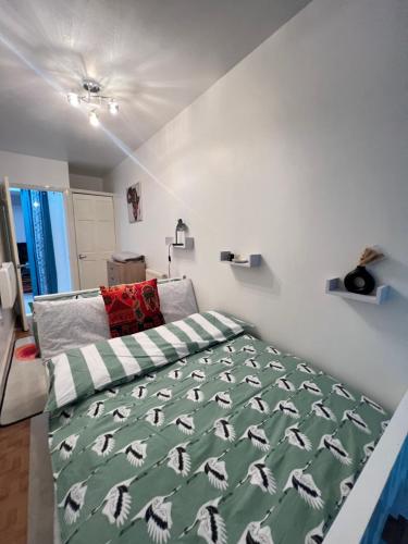 a bedroom with a bed with a green comforter at Crescent Apartment - Two bedroom in Goodmayes